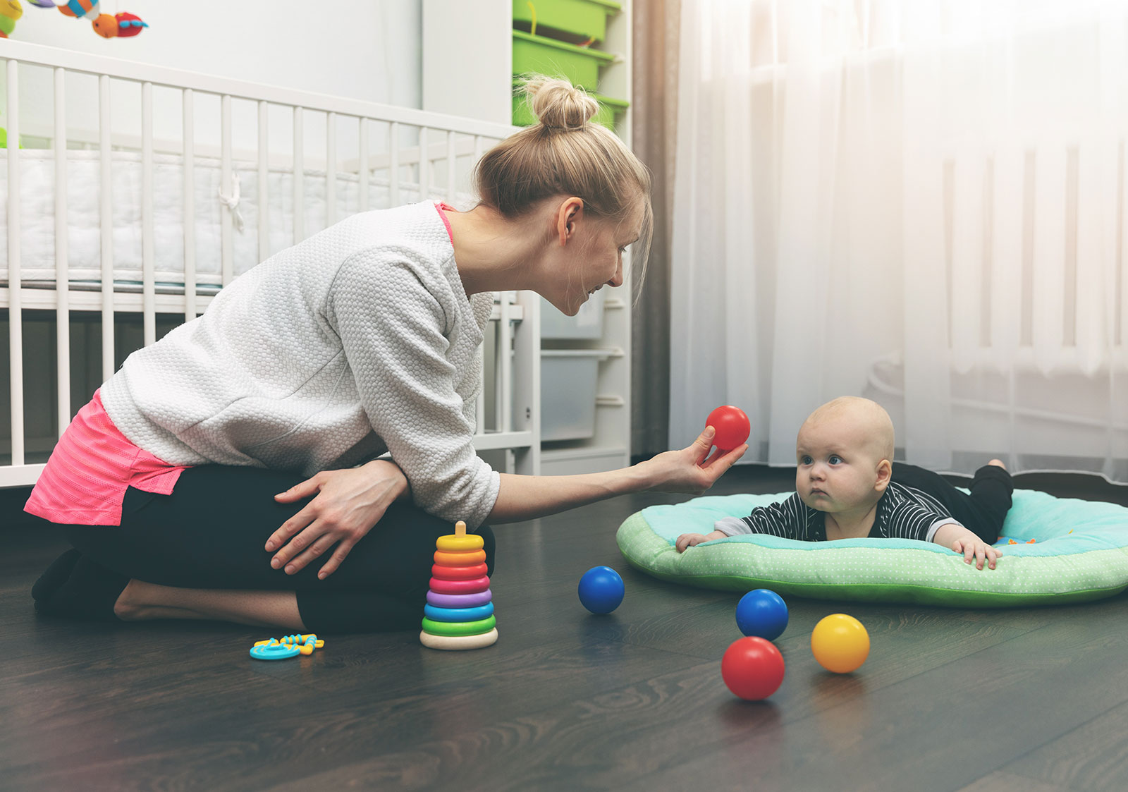 Nourrice qui s'occupe d'un bébé qui est sur un tapis d'éveil