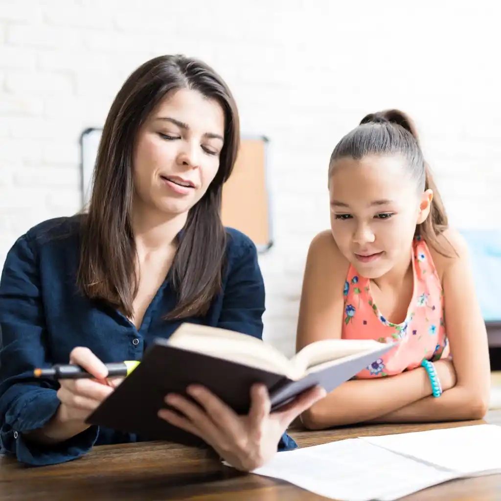 Une professeure explique un cours à une jeune fille de 12 ans en tenant un livre en main à Fameck