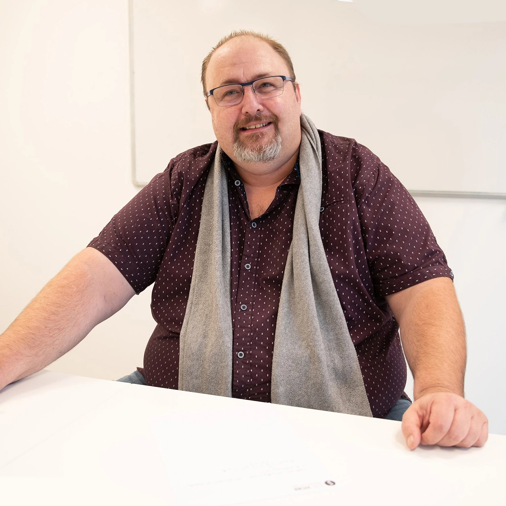Professeur de physique chimie Scol'Avenir devant un tableau blanc, assis à son bureau à Thionville