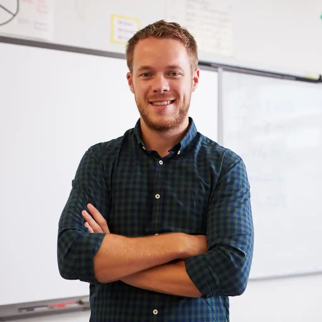 Un professeur de mathématiques souriant devant un tableau Scol’Avenir à Rombas