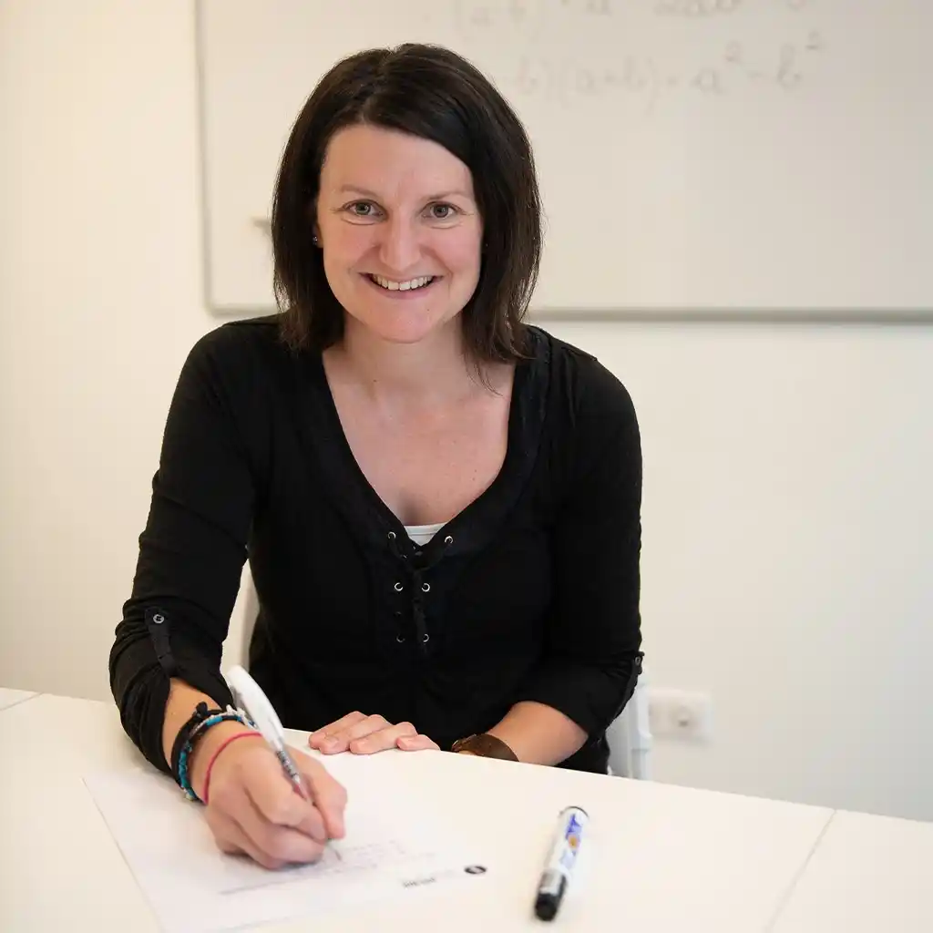 Une professeure de physique chimie Scol'Avenir écrit des formules à la craie sur un tableau