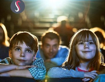 Deux enfants souriant regardant un film au cinéma