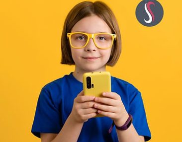Jeune enfant à lunette tenant un téléphone portable dans ses mains