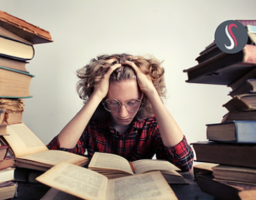 Elève se tenant la tête en lisant beaucoup de livres