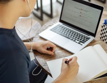 Elève qui travaille sur un devoir avec un ordinateur et une feuille