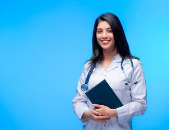 Medical concept of Asian beautiful female doctor in white coat with stethoscope, waist up. Medical student. Woman hospital worker looking at camera and smiling. Covid-19 pandemic.
