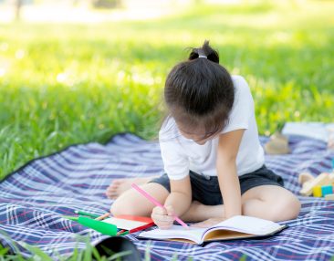 petite-fille-qui-fait-un-cahier-de-vacances-dehors
